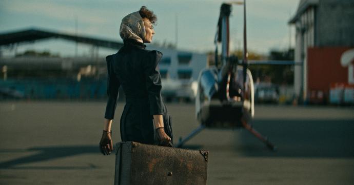 a woman in a black dress carrying a suitcase
